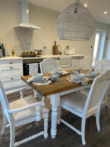 a kitchen with a wooden table and white chairs at The Pelican Room-converted Cart Lodge near airport in Horsham Saint Faith