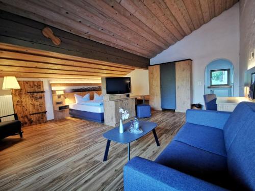 a living room with a blue couch and a bed at Gasthof & Hotel Zur Post in Wallgau