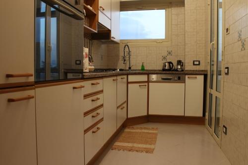a kitchen with white cabinets and a sink and a window at VI Floor Apartment in Rome