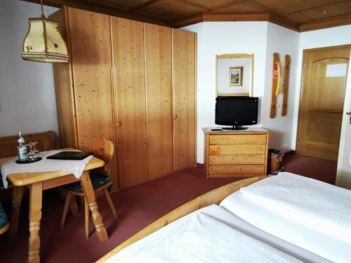 a bedroom with a bed and a desk and a tv at Gasthof & Hotel Zur Post in Wallgau