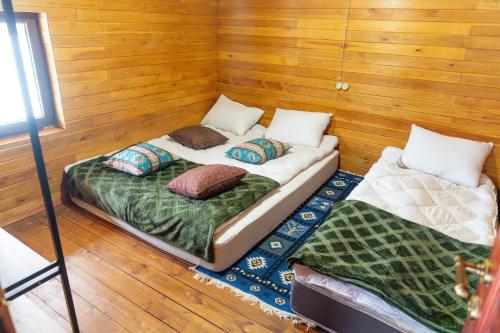 two twin beds in a room with wooden walls at Sakudela in Nikortsminda