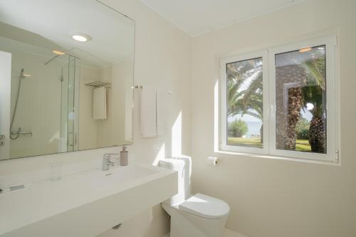 a white bathroom with a toilet and a window at Dune Beach CoLiving in Porto Santo