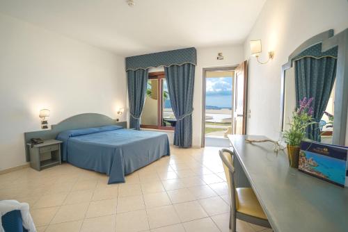 a bedroom with a blue bed and a table and a window at Hotel Scoglio Del Leone in Zambrone