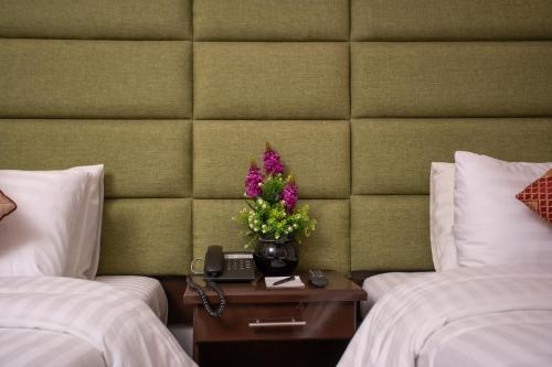 a hotel room with two beds and a table with flowers at Hotel One Swat in Swat