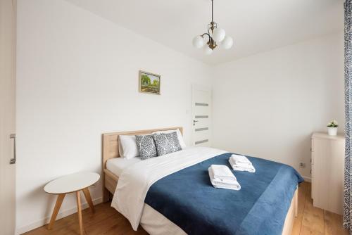 Mokotów Gaiety Place Apartment في وارسو: غرفة نوم بسرير وبطانية زرقاء وطاولة