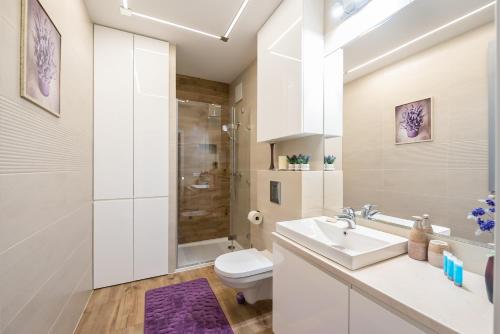 Mokotów Gaiety Place Apartment في وارسو: حمام أبيض مع حوض ومرحاض