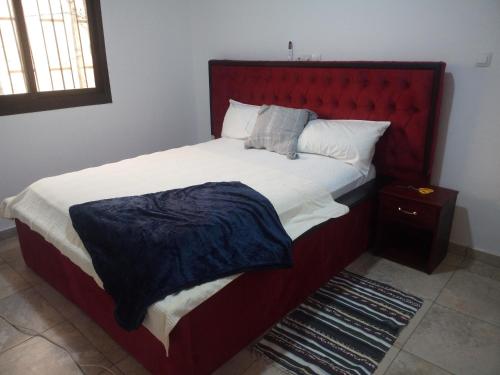 Schlafzimmer mit einem großen Bett mit einem roten Kopfteil in der Unterkunft Arbre de Paix 40/1.1 in Douala