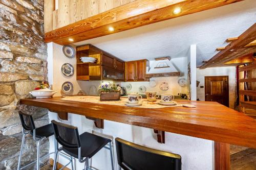 a kitchen with a large wooden counter with chairs at Arpy an in Morgex