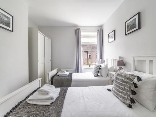 a white bedroom with two beds and a window at East House - Inviting 3 Bed Stakeford in Choppington