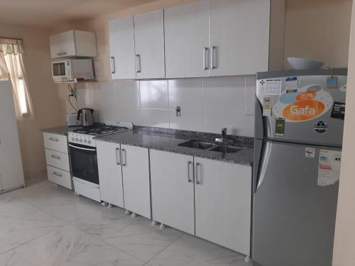 une cuisine avec des armoires blanches, un évier et un réfrigérateur dans l'établissement Aires del Pipo, à Ushuaia