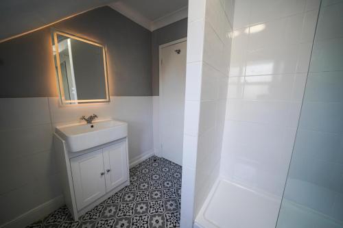 a white bathroom with a sink and a mirror at Gwydyr Hotel in Betws-y-coed