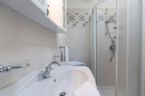 bagno bianco con lavandino e doccia di Maisonette a Portoferraio