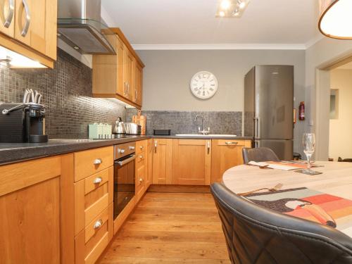 a kitchen with wooden cabinets and a table and a clock at Hillcroft in St Austell