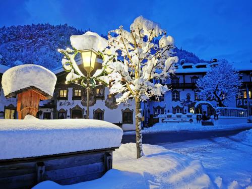 a tree covered in snow in front of a building at Gasthof & Hotel Zur Post in Wallgau