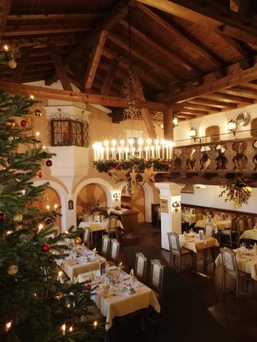 a christmas tree in a restaurant with tables and chairs at Gasthof & Hotel Zur Post in Wallgau