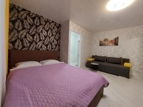 a bedroom with a purple bed and a couch at Стильні апартаменти Кравчука 10 LutskDoba in Lutsk