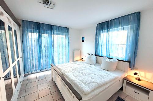 a bedroom with a large bed with blue curtains at Am Strand 2, PP innen in Zingst
