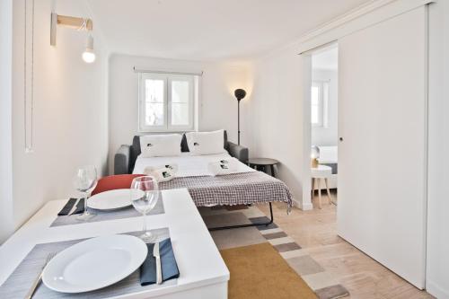 Habitación blanca con cama y mesa con copas de vino en BmyGuest - Alfama 1 Apartment en Lisboa