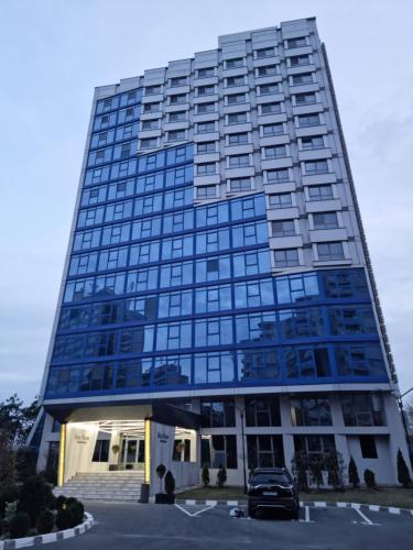 a tall glass building with a car parked in front at OLIMP Sea View Apartments - The Sunny Apartment in Olimp