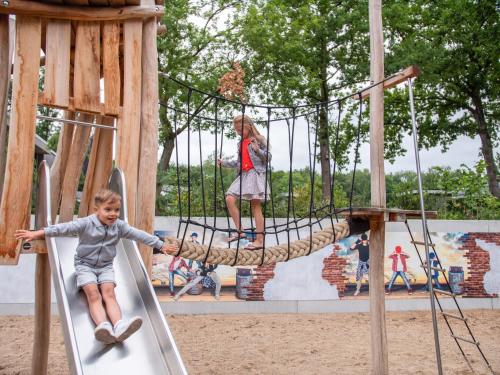 un niño en un columpio de cuerda en un patio de recreo en TopParken - Recreatiepark Beekbergen, en Beekbergen