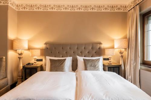 a bedroom with two beds and two lamps on tables at Boutiquehotel Weisses Rössl in Innsbruck