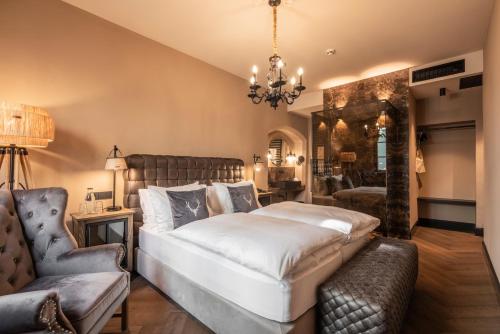 a bedroom with a large bed and a chair at Boutiquehotel Weisses Rössl in Innsbruck