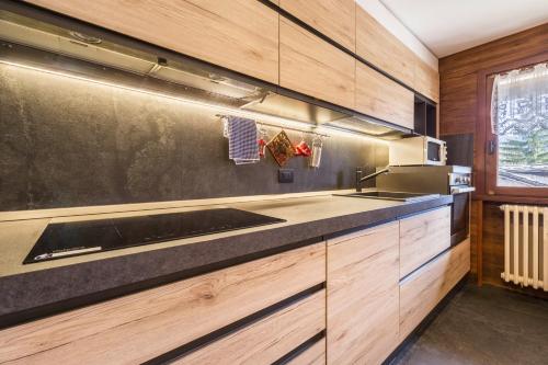 a kitchen with wooden cabinets and a sink at In centro a Courmayeur Mont Blanc in Courmayeur
