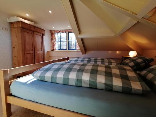 a bedroom with a bed with a checkered blanket at Holiday home bos en heide in Otterlo