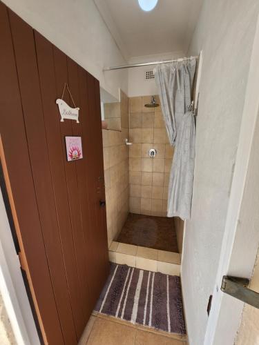 a small bathroom with a shower and a door at Aloe Self Catering in Port Shepstone