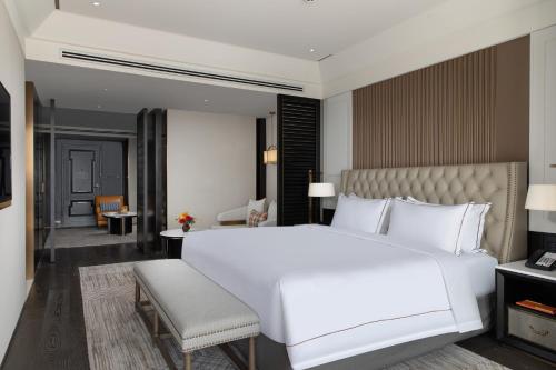 a bedroom with a large white bed and a chair at Suning Zhongshan Golf Resort in Nanjing