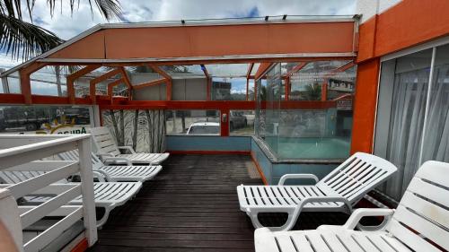 a group of white chairs sitting on a deck at Pousada Águas do Mariscal in Bombinhas