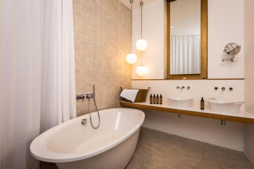 a bathroom with a tub and two sinks and a mirror at Hollmann Beletage Design & Boutique Hotel in Vienna