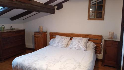 Schlafzimmer mit einem Bett mit weißer Bettwäsche und Holzmöbeln in der Unterkunft Gîte d'en Pouillac in Saint-Thomas