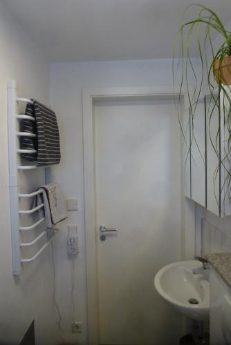 een witte badkamer met een deur en een wastafel bij Gästezimmer am Flissertwald in Heuweiler