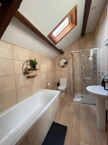 a bathroom with a tub and a toilet and a sink at Cilhendre Holiday Cottages - The Dairy in Swansea
