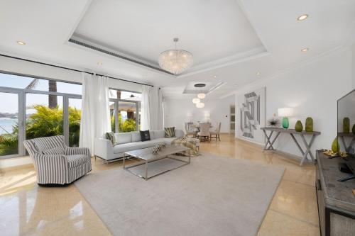 a living room with white furniture and large windows at Maison Privee - Exclusive Villa with Private Pool, Garden & Beach in Dubai