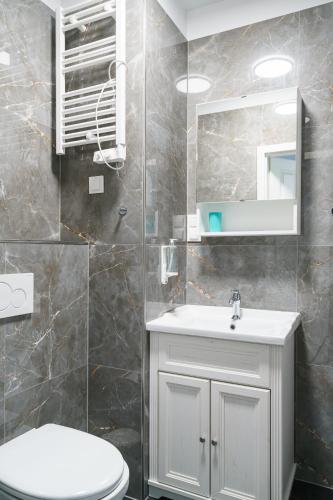 a bathroom with a toilet and a sink and a mirror at RentPlanet - Apartamenty Zarembowicza II in Wrocław