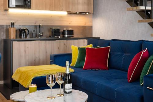 a blue couch with red and green pillows and wine glasses at Rezydencja Strążyska & Chalet BBQ in Zakopane