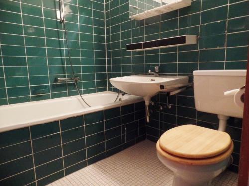 uma casa de banho com azulejos verdes, um WC e um lavatório. em Ferienpark Sierksdorf App 425 - Strandlage em Sierksdorf