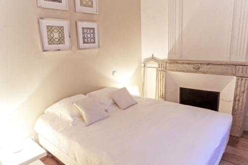 Cama blanca con almohadas en una habitación con chimenea en Saint Rémi - Appartement 1 chambre avec ascenseur en Burdeos