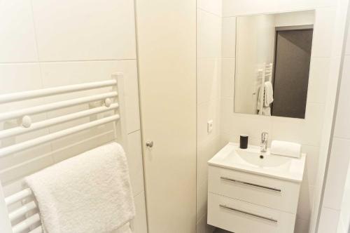 W białej łazience znajduje się umywalka i lustro. w obiekcie Saint Rémi - Appartement 1 chambre avec ascenseur w mieście Bordeaux