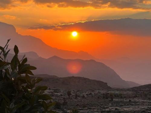 a sunset over a city with mountains in the background at Jabal Shams bayt kawakib in Misfāh