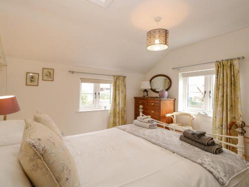 a bedroom with a large white bed and two windows at Cosy Cottage in Bawdeswell