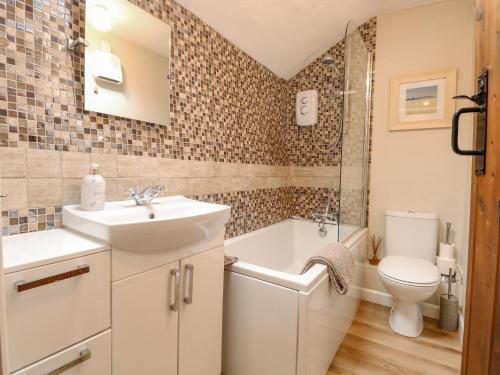 a bathroom with a sink and a tub and a toilet at Cosy Cottage in Bawdeswell