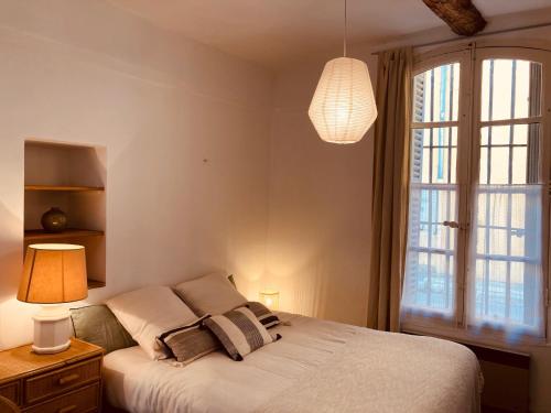 une chambre avec un lit avec une lampe et une fenêtre dans l'établissement Appartement de charme au coeur du vieux Aix., à Aix-en-Provence