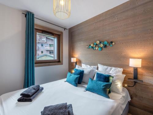 une chambre avec un grand lit blanc avec des oreillers bleus dans l'établissement Appartement neuf à Megève avec piscine et espace détente - FR-1-569-25, à Megève