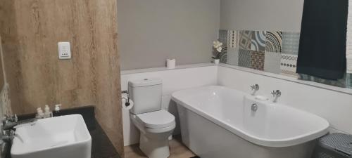 La salle de bains blanche est pourvue de toilettes et d'un lavabo. dans l'établissement Beach Club 404, à Mossel Bay