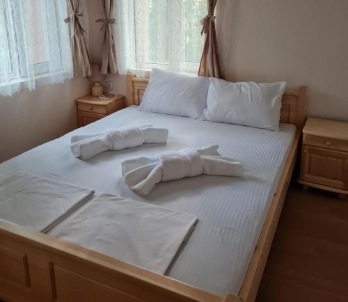 un letto con lenzuola bianche e 2 cuscini sopra di Вила Вайлин a Batak