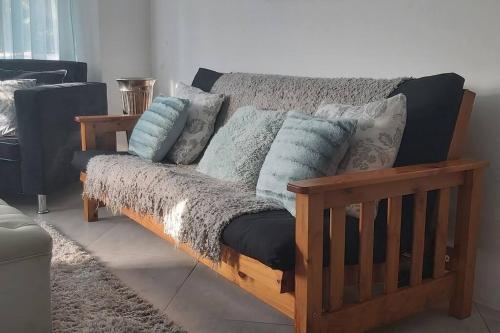 a wooden couch with pillows on it in a living room at Phoenix, Langenhovenpark, Bfn near Inibos parkrun. in Bloemfontein