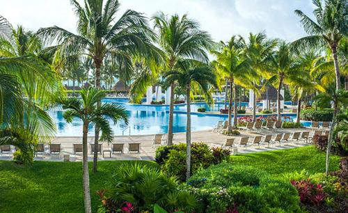 um resort com uma grande piscina com palmeiras em Resort Vidanta Riviera Maya em Puerto Morelos